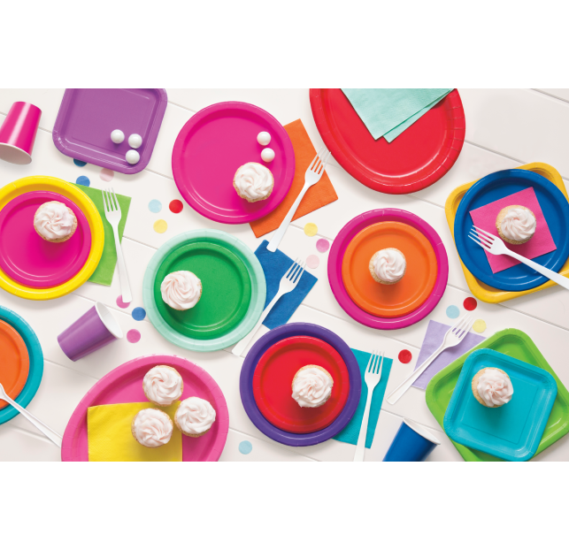 Colorful tea cups and saucers arranged with sweets and spoons.