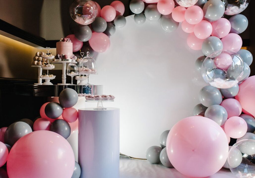 Pink and gray balloon arch with desserts.